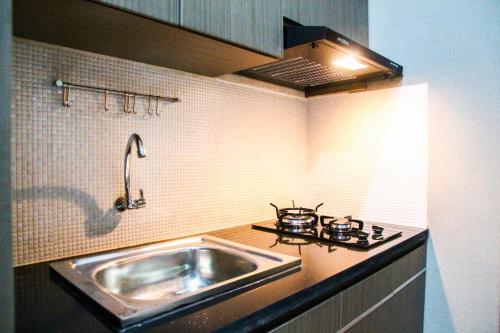 a kitchen with a sink and a stove at New Studio The Oasis Apartment By Travelio in Cikarang