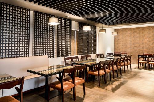 uma fila de mesas e cadeiras num restaurante em The Mayberry -A Bergamont Group of Hotels em Tiruppūr