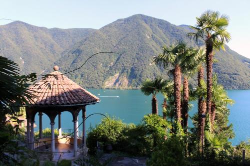 a gazebo with palm trees in front of a lake at Barony Le Pergole Lugano Villa for 8 persons in Lugano