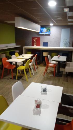 a dining room with tables and chairs and a tv at ibis budget Dieppe Centre Port in Dieppe