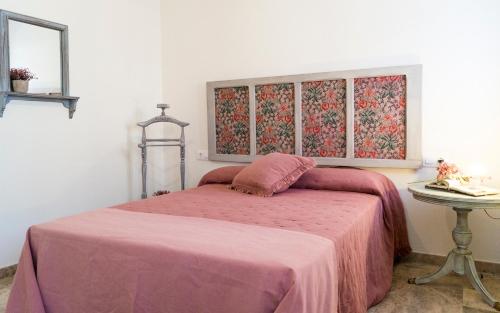 - une chambre avec un lit avec une couverture rose et une table dans l'établissement Capitulares, à Cordoue