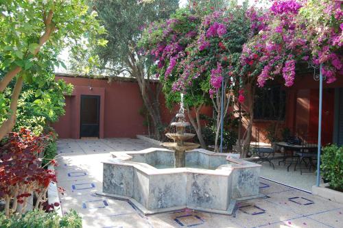a fountain in the middle of a courtyard with flowers at Riad les jardins Mabrouk in Taroudant
