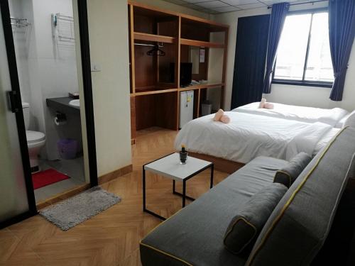 a bedroom with two beds and a couch and a mirror at Double D Rooms & Cafe in Bangkok