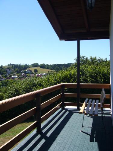 a bench sitting on a porch with an umbrella at Haus Gieselsberg, mit Aussicht auf Schmalkalden in Schmalkalden