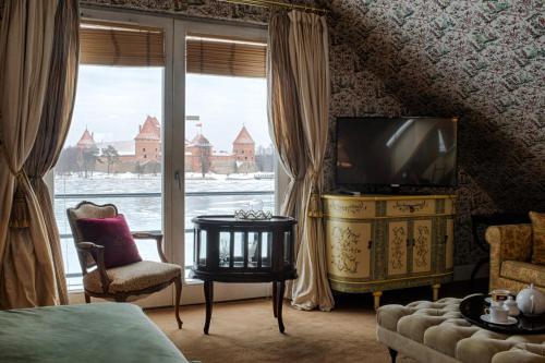 a bedroom with a television and a large window at Apvalaus Stalo Klubas Gastro & SPA Hotel in Trakai