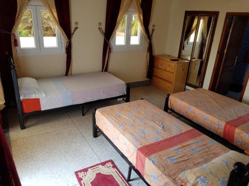 Habitación con 3 camas, vestidor y ventanas. en Hotel Canarias Sahara en Tan-Tan Plage