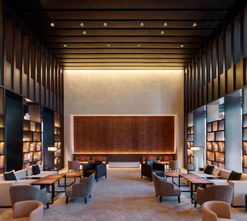 una biblioteca con mesas, sillas y una pantalla grande en The PuXuan Hotel and Spa, en Beijing