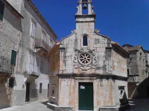 an old building with a clock tower with a green door at Apartments and Rooms Dobrila in Jelsa