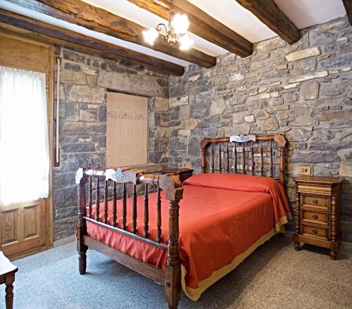 a bedroom with a bed and a stone wall at Apartamentos Casa Buisan in Broto