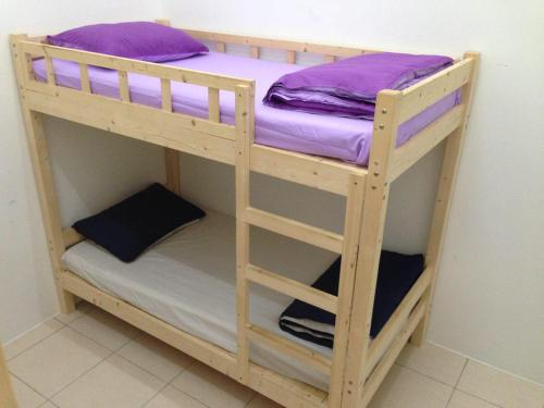 セリ・イスカンダルにあるNUHA HOMESTAYの木製の二段ベッド(紫色の枕付)