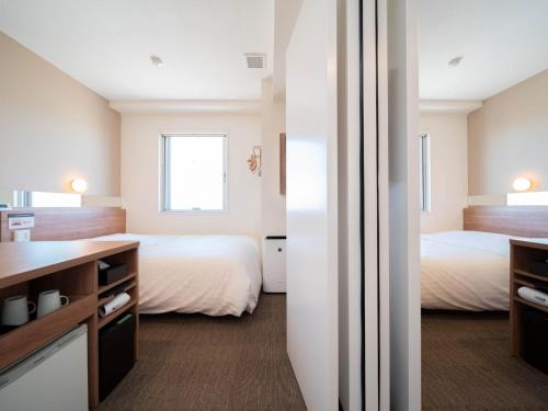 a hotel room with two beds and a bathroom at Super Hotel Yamagata Sakurambo-Higashine Station Front in Higashine