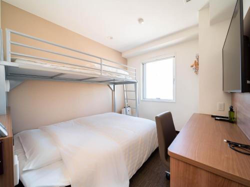 a bedroom with a bunk bed and a desk at Super Hotel Yamagata Sakurambo-Higashine Station Front in Higashine