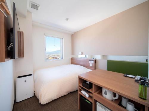 a hotel room with a bed and a desk at Super Hotel Yamagata Sakurambo-Higashine Station Front in Higashine