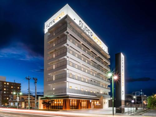 um grande edifício branco com um cartaz em Super Hotel Yamagata Sakurambo-Higashine Station Front em Higashine