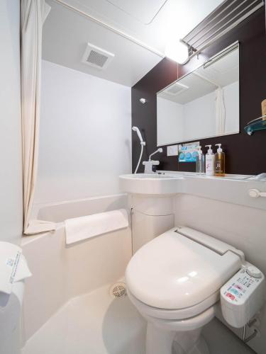 a white bathroom with a toilet and a sink at Super Hotel Yamagata Sakurambo-Higashine Station Front in Higashine