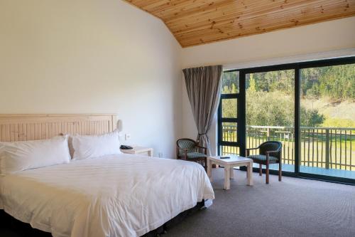 a bedroom with a bed and a large window at Houw Hoek Hotel in Botrivier