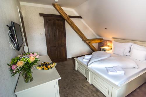 a small bedroom with a bed and a vase of flowers at Boutique Hotel Annuska in Balatonfüred