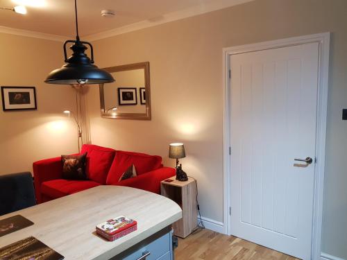a living room with a red couch and a table at Smart & Cozy Holiday Apartment in the city centre in Inverness