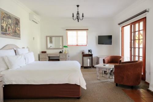 a bedroom with a bed and a chair and a television at Houw Hoek Hotel in Botrivier