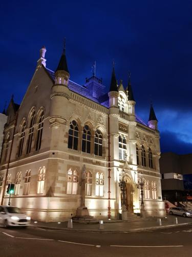a building lit up at night with a car in front at Smart & Cozy Holiday Apartment in the city centre in Inverness