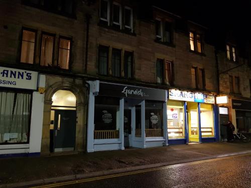a row of store fronts on a street at night at Smart & Cozy Holiday Apartment in the city centre in Inverness