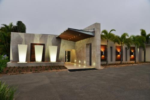 a modern home with a large building with palm trees at BON Hotel Empangeni in Empangeni