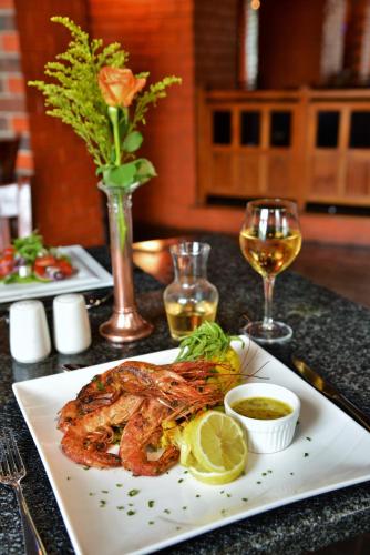 a plate of food with shrimp and a glass of wine at BON Hotel Empangeni in Empangeni