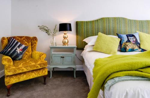 a bedroom with a bed and a chair with a green blanket at The Post House Hotel - no children under the age of 16yrs in Greyton