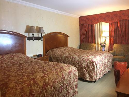 a hotel room with two beds and a chair at Acorn Motor Inn in Oak Harbor
