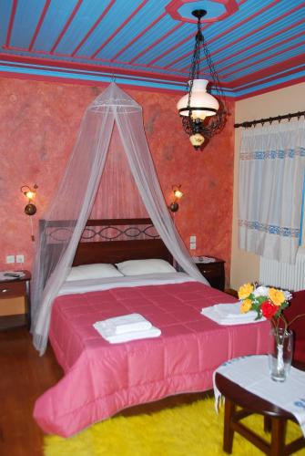 a bedroom with a pink bed with a mosquito net at Hotel Ladias in Monodendri