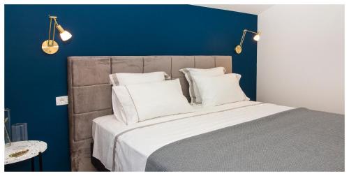 a bed with white pillows and a blue wall at Apartman Sissy in Primošten