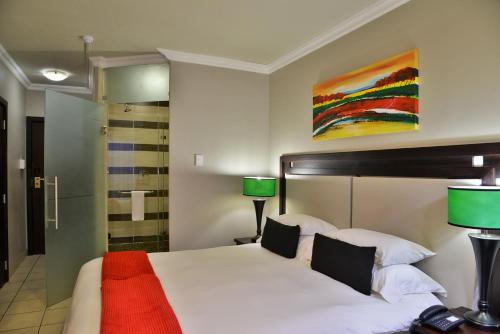 a bedroom with a large bed with two lamps at BON Hotel Empangeni in Empangeni