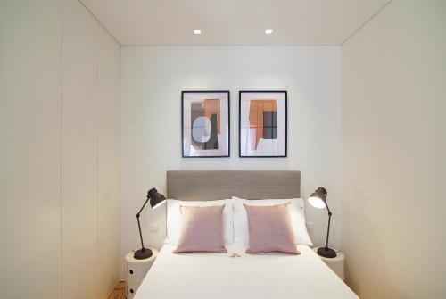 een witte slaapkamer met 2 lampen en een bed bij HM - The Garden in Porto