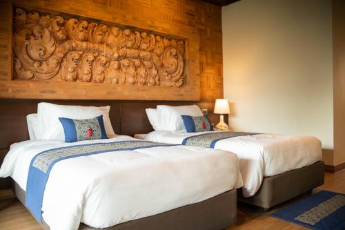 two beds in a hotel room with a headboard at Phor Liang Meun Terracotta Arts in Chiang Mai