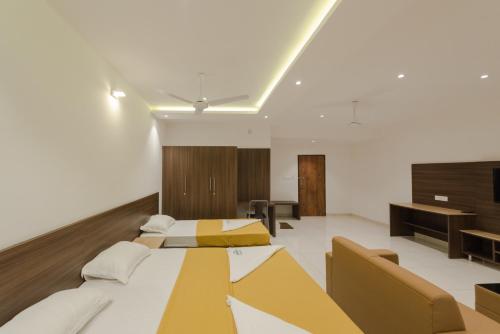 a large room with two beds and a desk at Hotel Karuna Residency in Mangalore