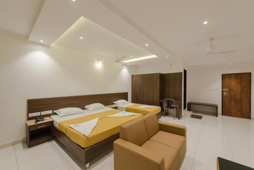 a bedroom with two beds and a couch at Hotel Karuna Residency in Mangalore