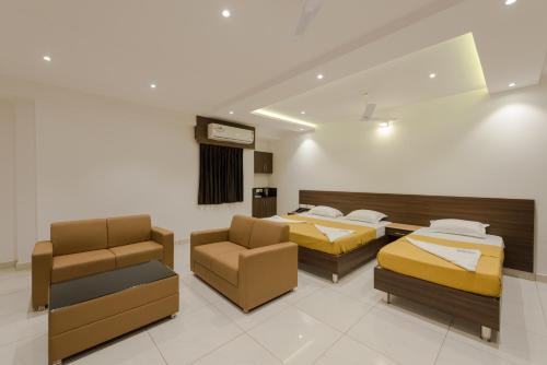 a hotel room with two beds and a couch and chairs at Hotel Karuna Residency in Mangalore