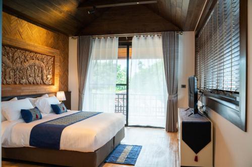 a bedroom with a large bed and a television at Phor Liang Meun Terracotta Arts in Chiang Mai