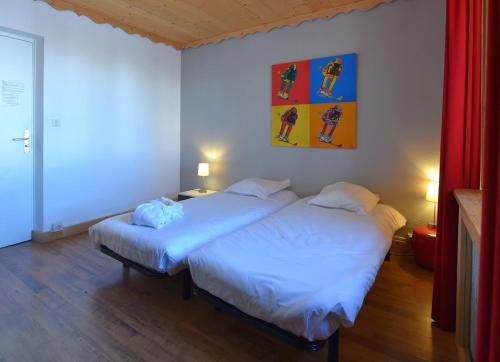 ラ・トゥッスイールにあるLa Principauté de Comborciereの赤いカーテン付きの客室で、ツインベッド2台が備わります。