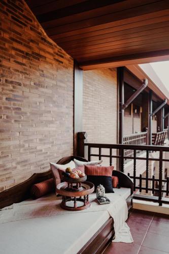 a balcony with a table and a brick wall at Phor Liang Meun Terracotta Arts in Chiang Mai