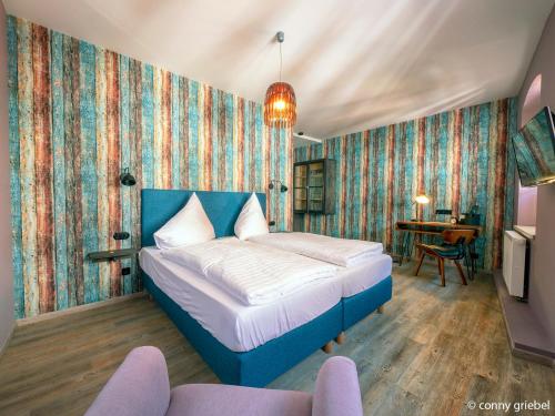 a bedroom with a blue bed in a room with wallpaper at Hotel - Weinbar FAHR AWAY in Volkach