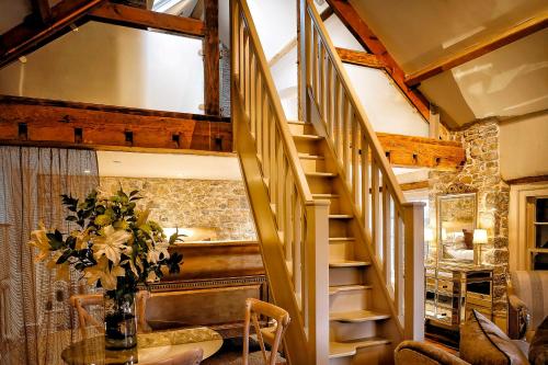 a room with a staircase and a table with a vase of flowers at Gileston Manor-Self catering in Saint Athans