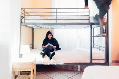 a woman sitting on a bed in a bunk bed at The Beehive in Rome