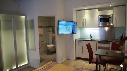 a kitchen with a toilet and a tv on the wall at Aparthotel Kottenforst in Bonn