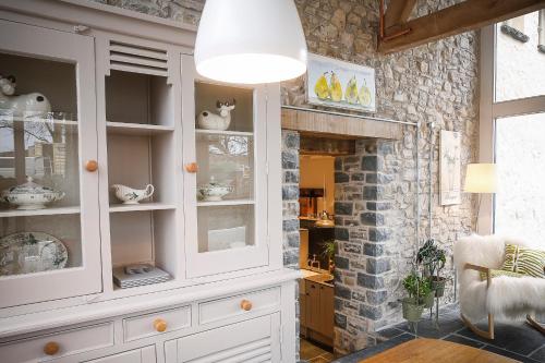 a kitchen with white cabinets and a brick wall at Gileston Manor-Self catering in Saint Athans