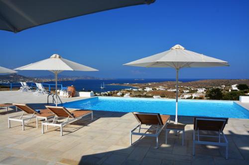 Grupa krzeseł i parasoli obok basenu w obiekcie White Blue Houses & Apartments Paros w mieście Parikia