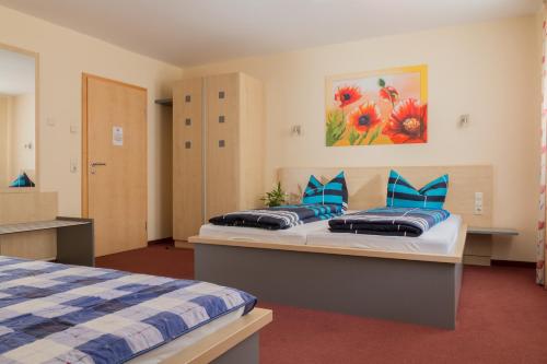 a bedroom with two beds with blue pillows at Hotel Papillon in Lappersdorf
