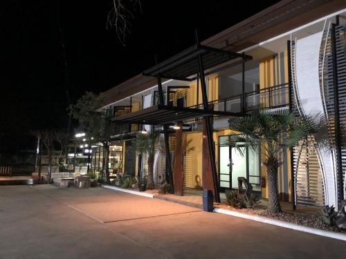 a building with palm trees in front of it at night at The C Hotel in Amnat Charoen