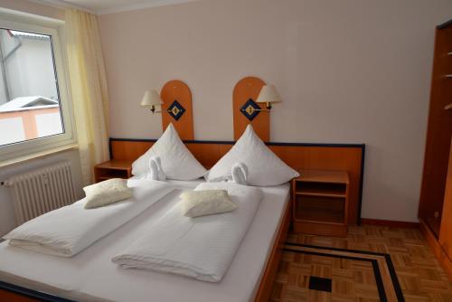 1 Schlafzimmer mit 2 Betten mit weißer Bettwäsche und einem Fenster in der Unterkunft Pension Francesco in Nürnberg