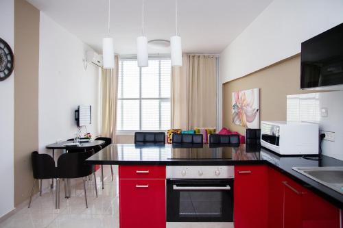 cocina con armarios rojos y encimera negra en Apartment Happiness, en Bat Yam